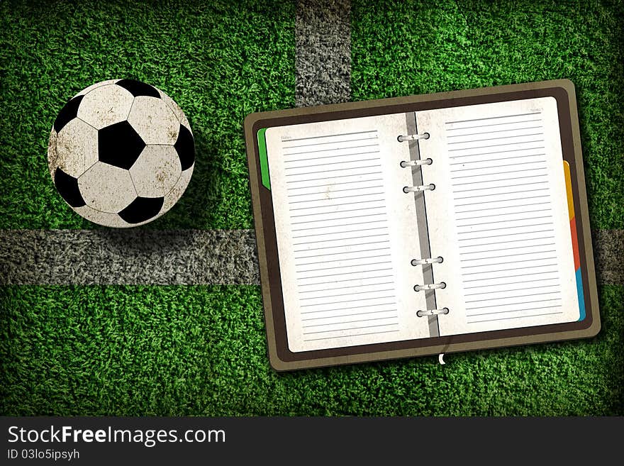 Football and blank notebook on Green Grass background