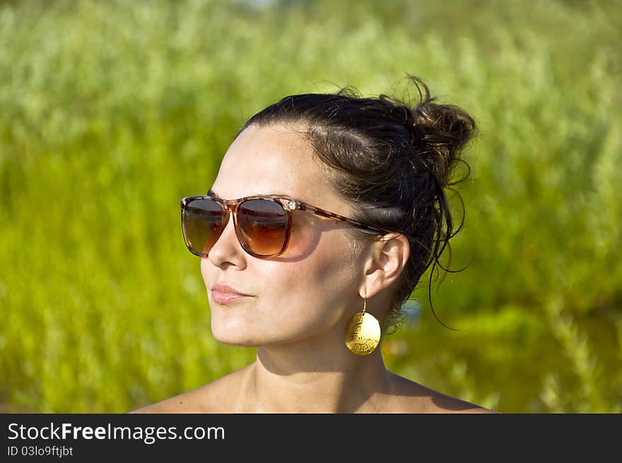 Beautiful young girl in sunglasses on the beach. Portrait. Blurred background. Summer portrait.