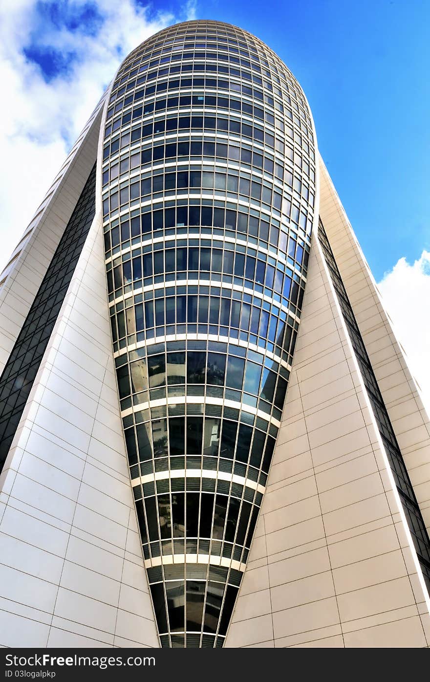 High-rise office building its modern glass and concrete in the shape of the sail against the sky. High-rise office building its modern glass and concrete in the shape of the sail against the sky