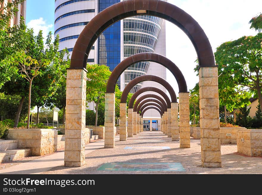 Alley of metal arches on stone pillars leading to an office building. Alley of metal arches on stone pillars leading to an office building