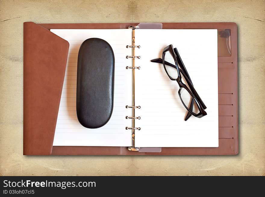 Reading glasses on white notebook