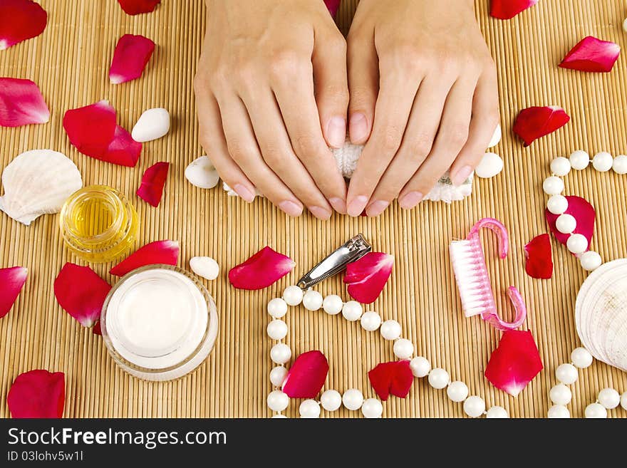 Close-up of girl lying on hand towel next to the cream, rose petals and manicure equipment. Close-up of girl lying on hand towel next to the cream, rose petals and manicure equipment