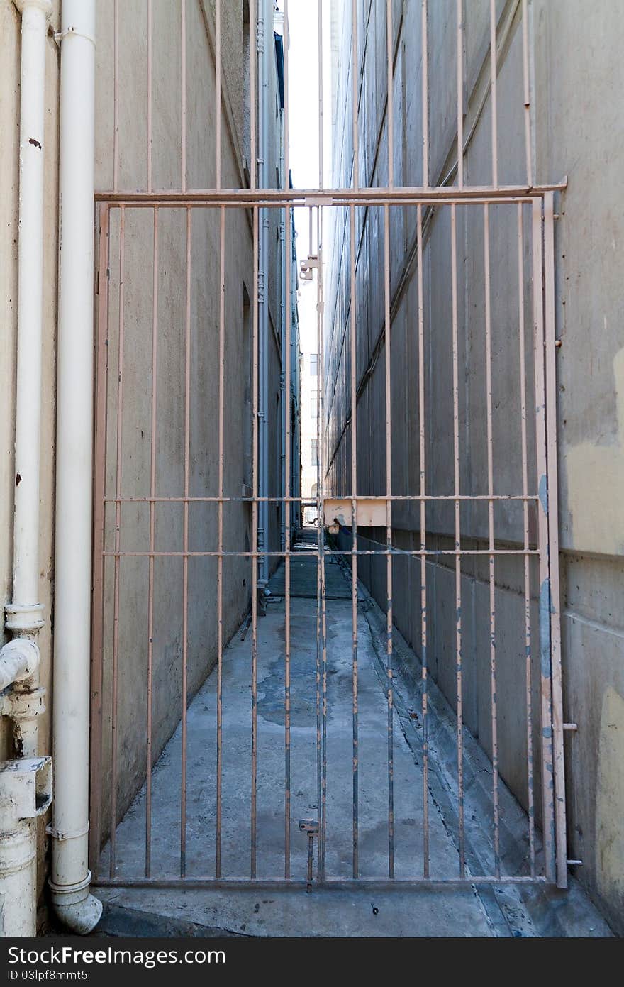 Looking down a long gated alleyway that is deserted.