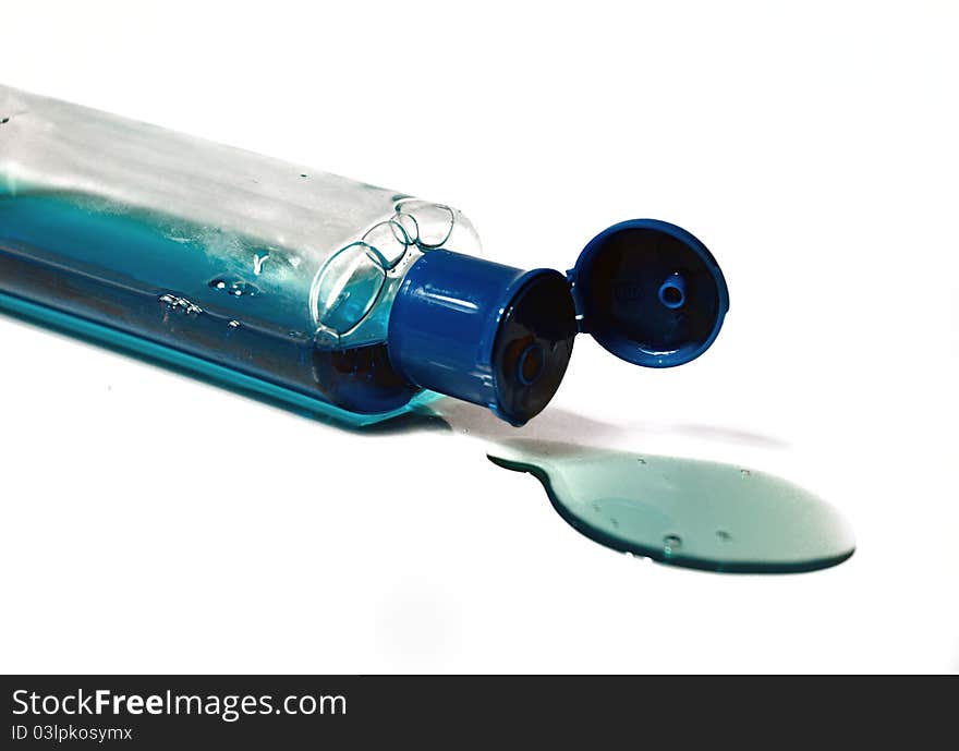 Bottle of blue liquid spilled away, isolated