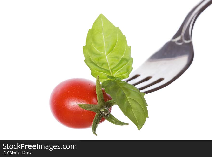 Fork with basil and tomato on white background