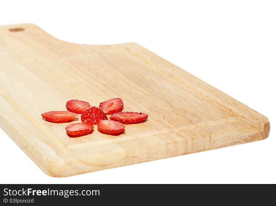 Flower, made of fresh strawberries on a kitchen hardboard on a white background