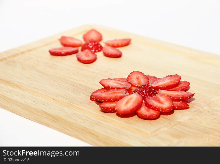 Flower, made of fresh strawberries on a kitchen hardboard