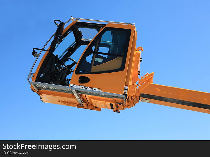 Operated cabin of the elevating crane against the sky. Operated cabin of the elevating crane against the sky