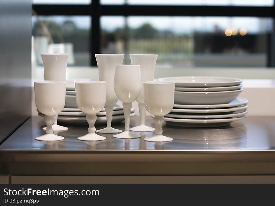 White wineglasses and plates on a worktop. White wineglasses and plates on a worktop.