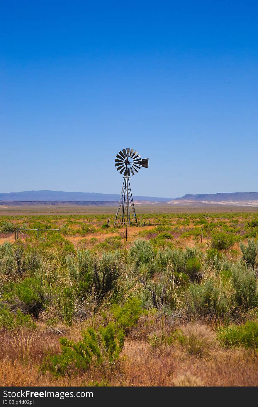 A scene in the western United States (Nevada), with an old-fashioned windmill, desert landscape and a bright blue sky. Lots of copy space. A scene in the western United States (Nevada), with an old-fashioned windmill, desert landscape and a bright blue sky. Lots of copy space.