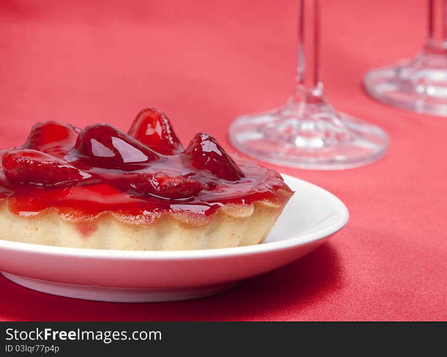 Strawberry cake topped with strawberry glaze on red satin background