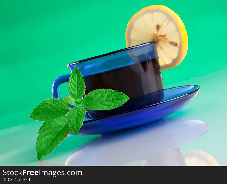 Nice cup of tea and mint on green background