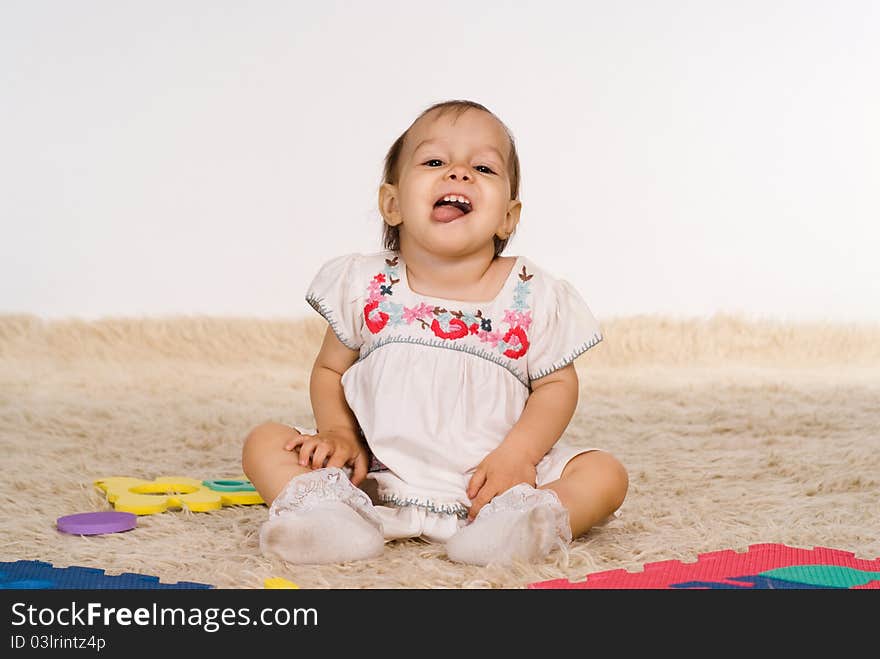 Funny little girl playing on the carpet