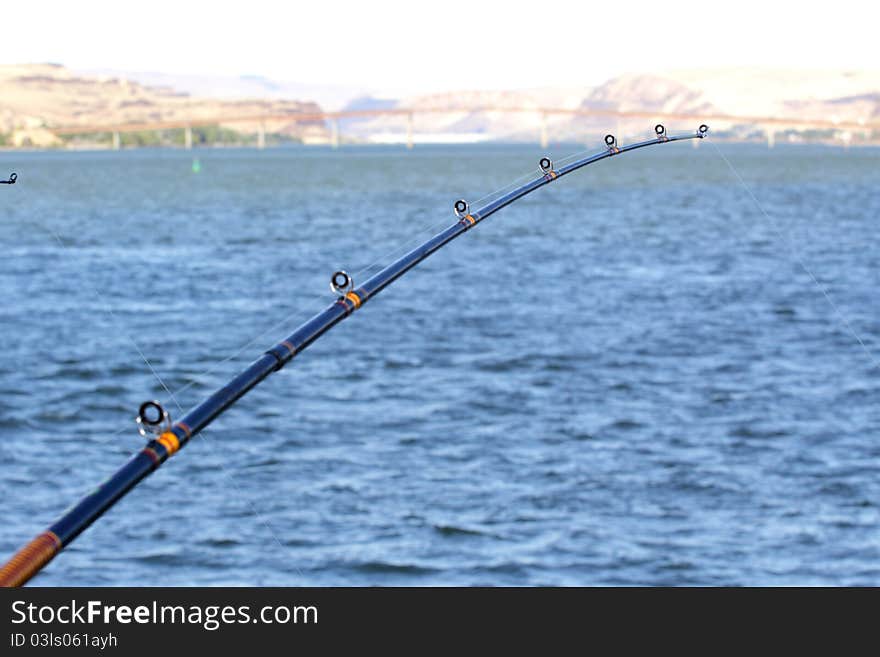 Sturgeon fishing reel and pole. Columbia River with Maryhill Bridge muted in the background. Extreme shallow depth of field with selective focus. Sturgeon fishing reel and pole. Columbia River with Maryhill Bridge muted in the background. Extreme shallow depth of field with selective focus.