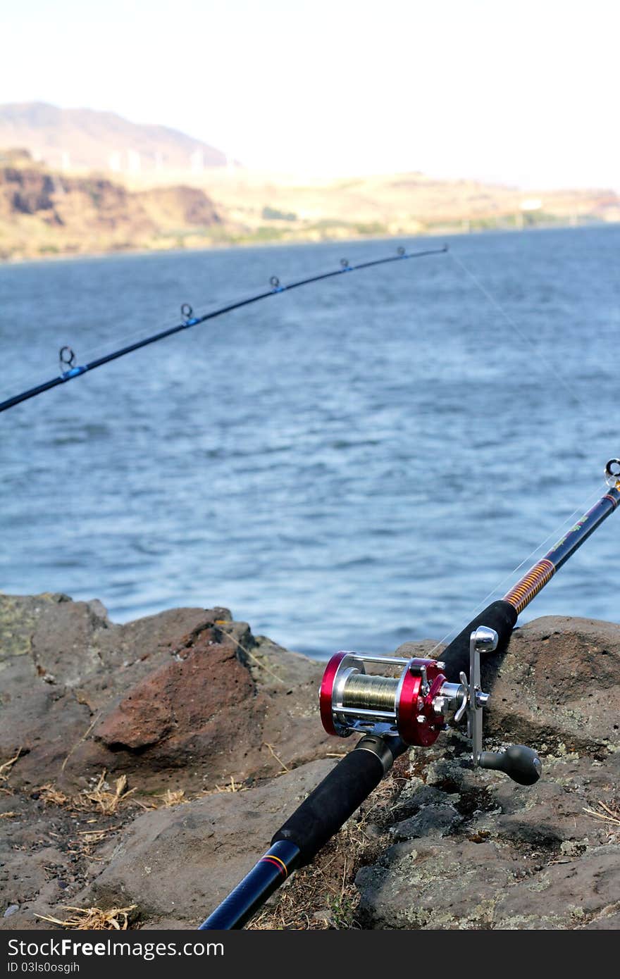 Two fishing poles. Columbia River with rocks in foreground. Extreme shallow depth of field with selective focus. Two fishing poles. Columbia River with rocks in foreground. Extreme shallow depth of field with selective focus.