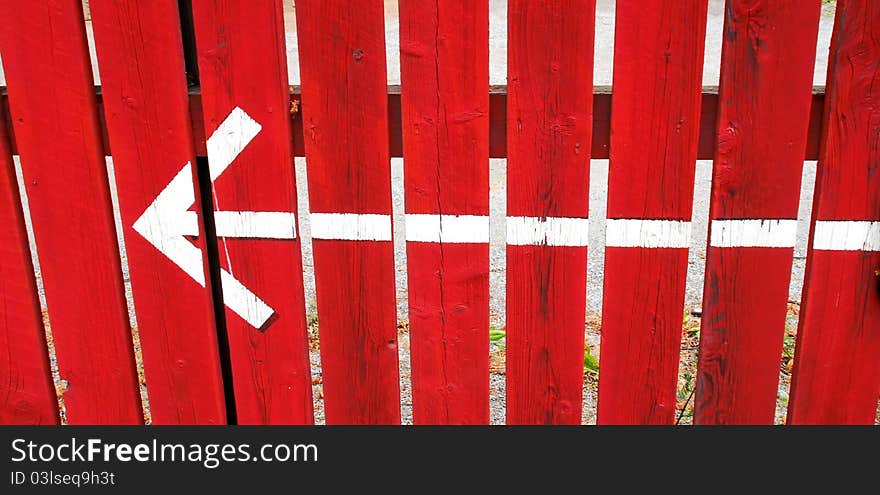 Indicating arrow painted on red fence. Indicating arrow painted on red fence