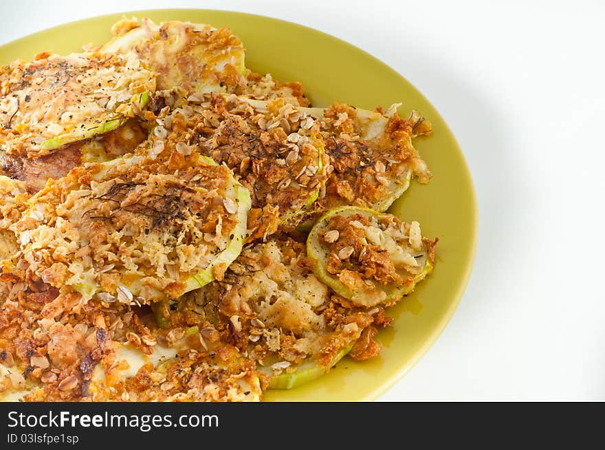 Healthy Zucchini baked in electrical oven , on a green plate isolated on a white background