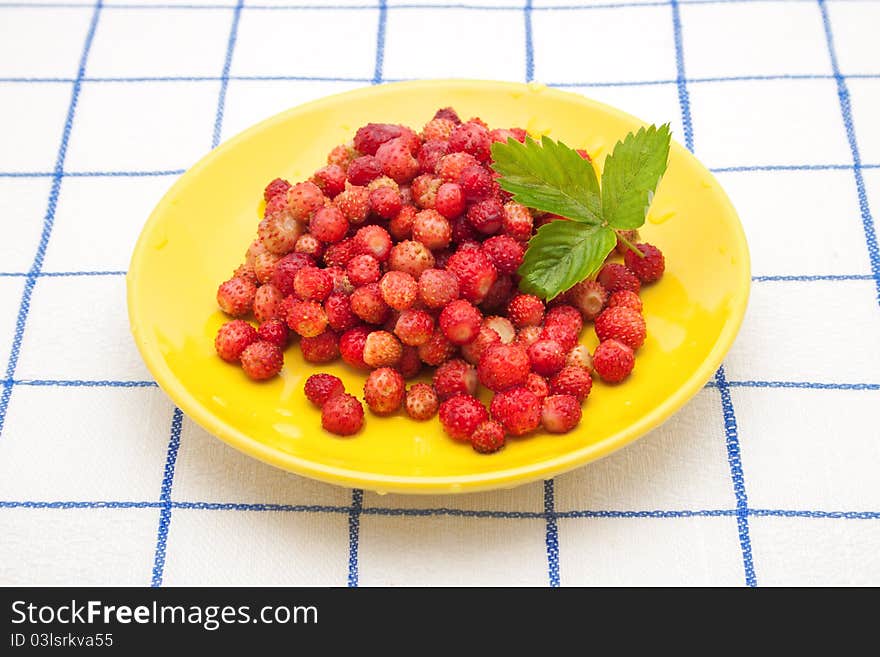 Strawberries on a yellow plate with green leaf