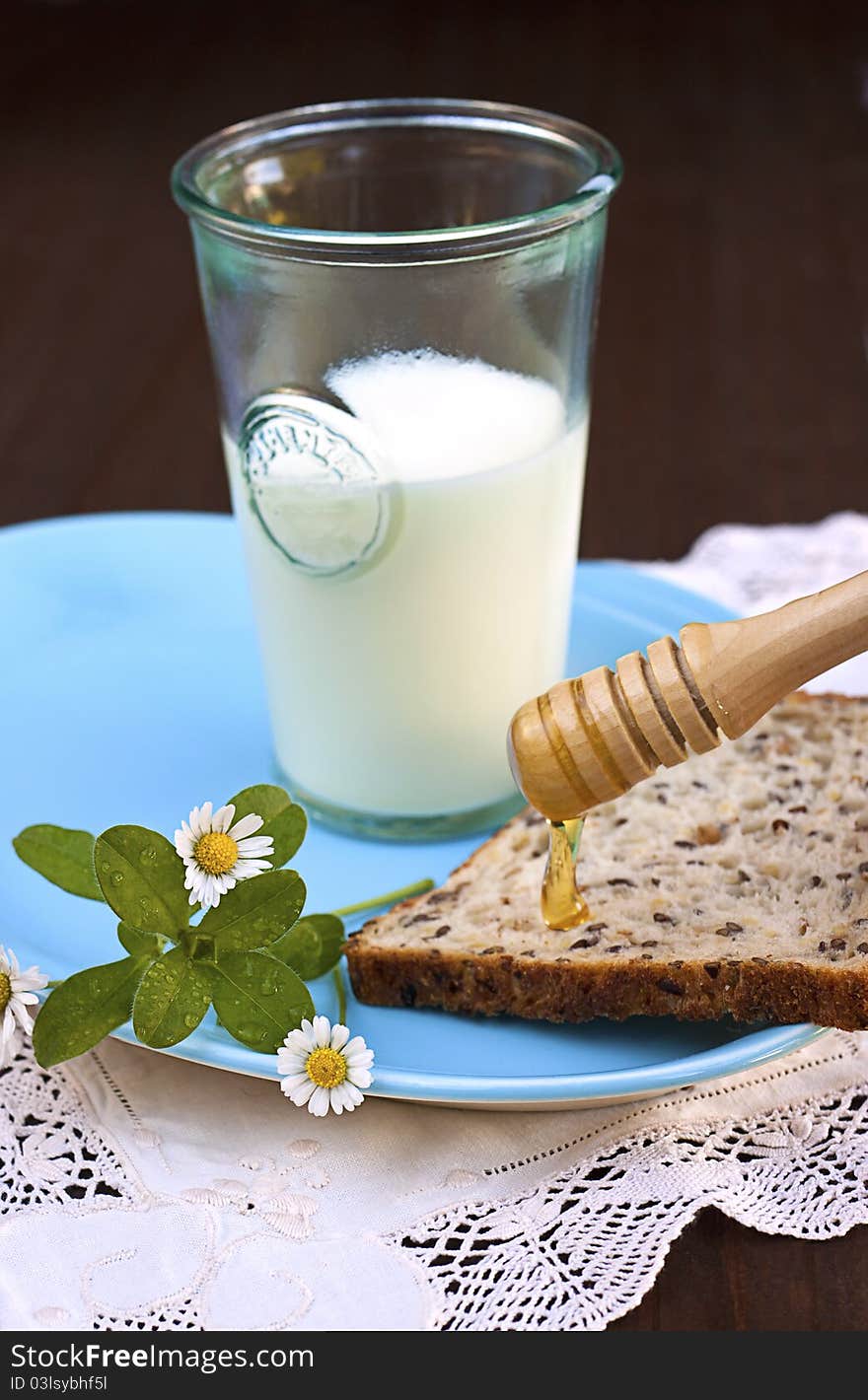 Healthy breakfast - glass of milk, multigrain toast and golden honey running from wooden drizzler. Healthy breakfast - glass of milk, multigrain toast and golden honey running from wooden drizzler