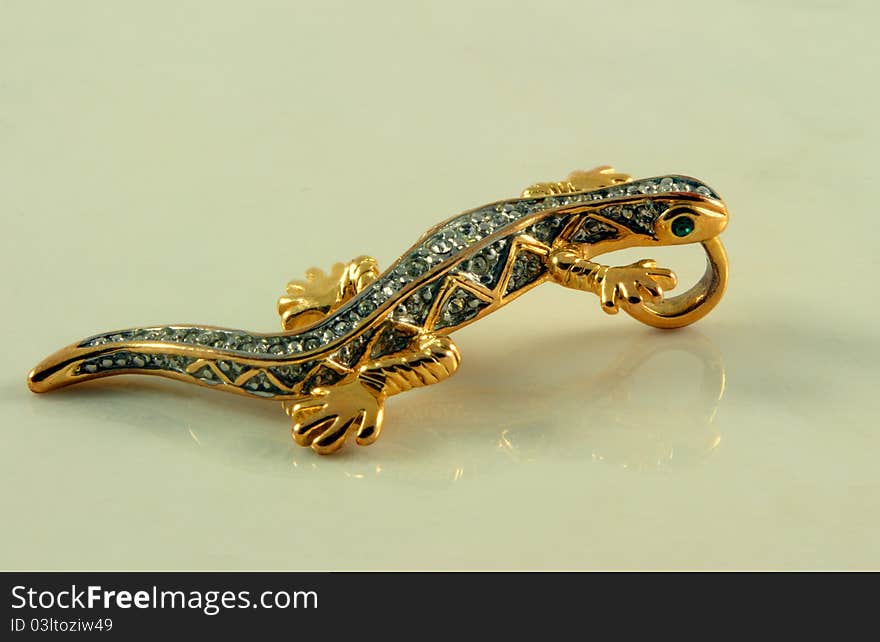 Jewelry in shape of lizard with stones on marble surface. Jewelry in shape of lizard with stones on marble surface