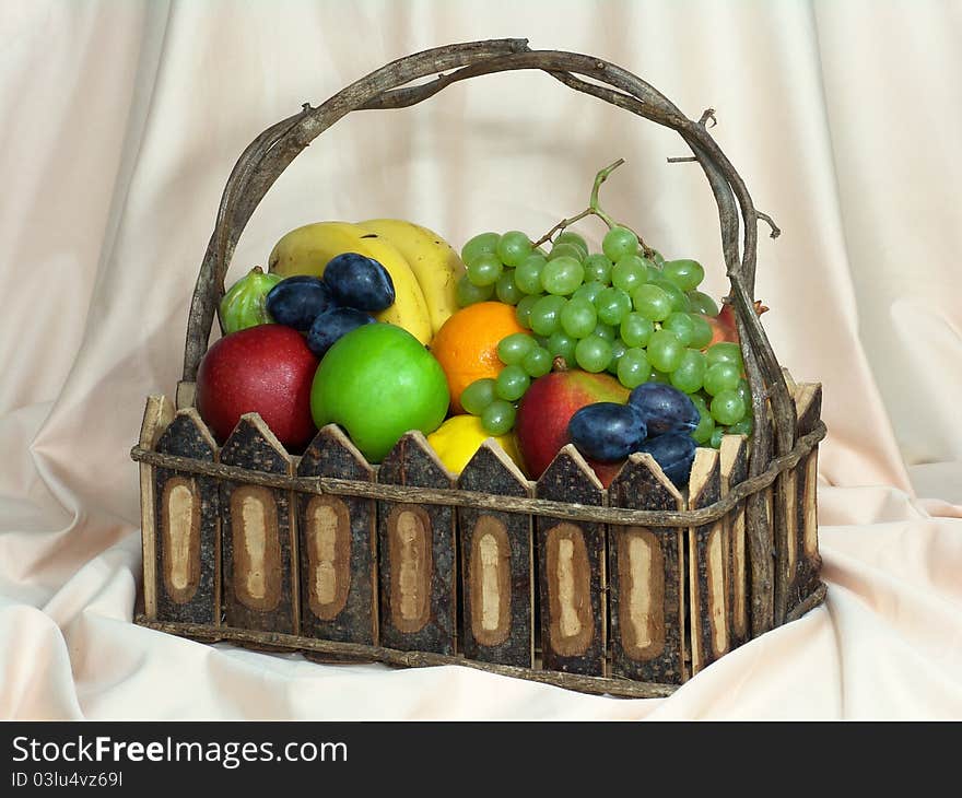 A shot of fruits in a basket with piece of cloth behind it