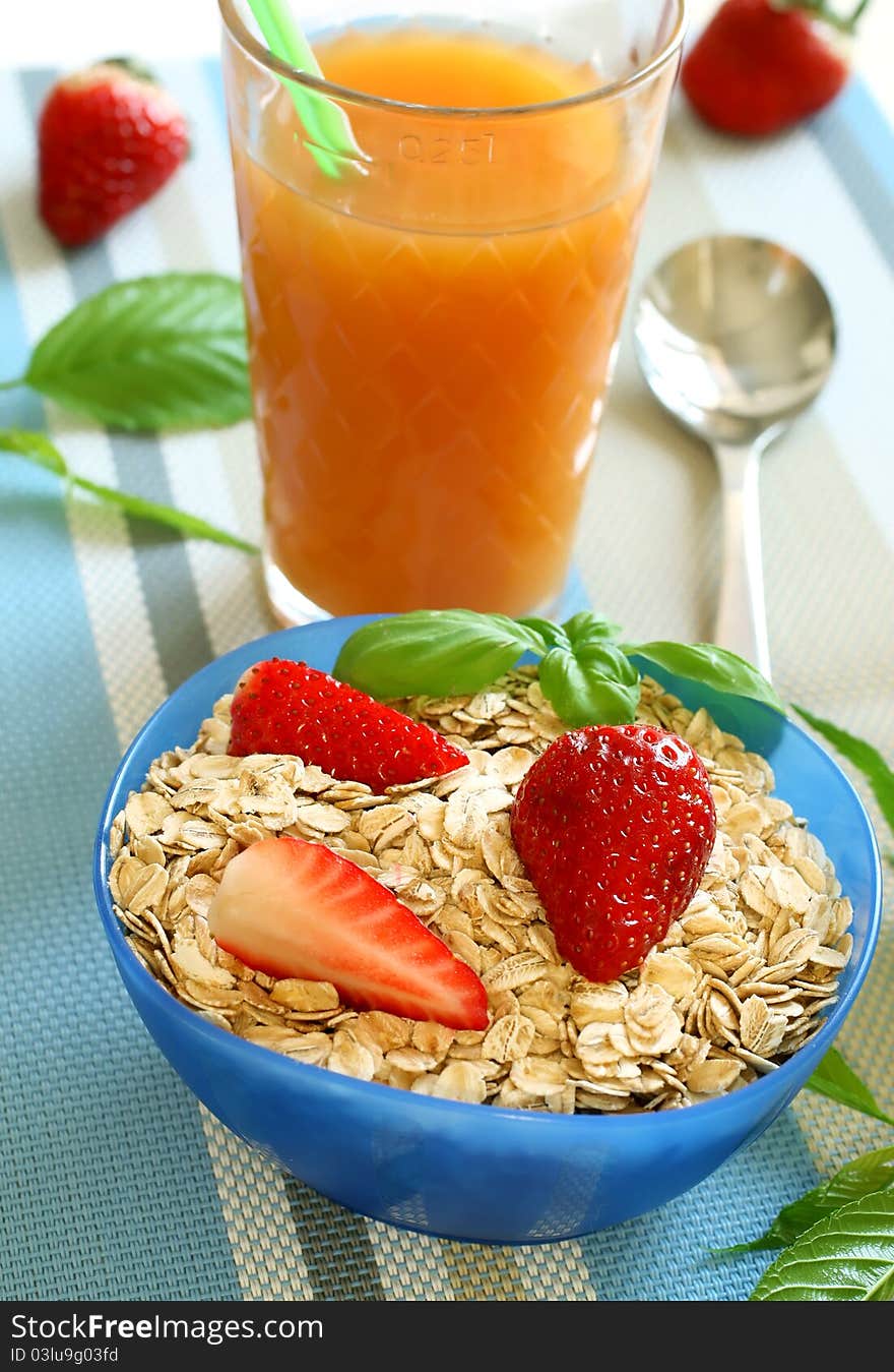 Oats and strawberry in bowl and glass of juice - diet breakfast