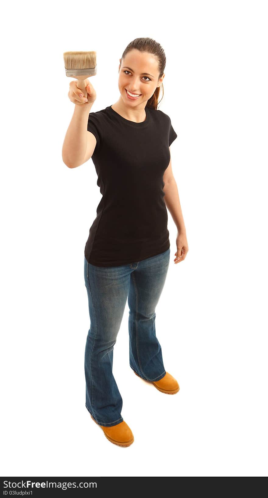 A young female dressed in a black t shirt and blue jeans holding a paint brush. A young female dressed in a black t shirt and blue jeans holding a paint brush