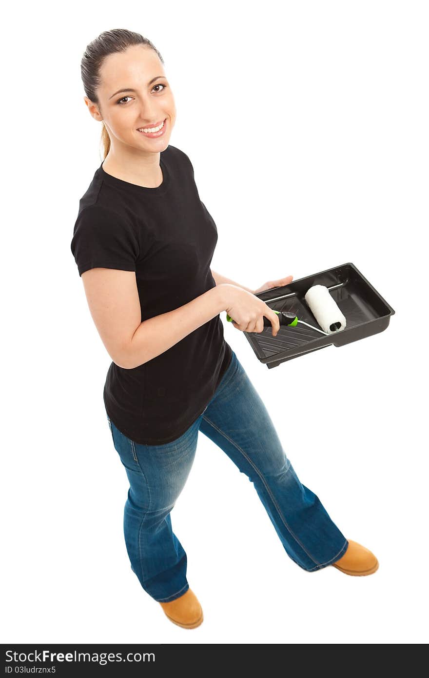 A young female dressed in a black t shirt and blue jeans holding a paint roller and tray. A young female dressed in a black t shirt and blue jeans holding a paint roller and tray