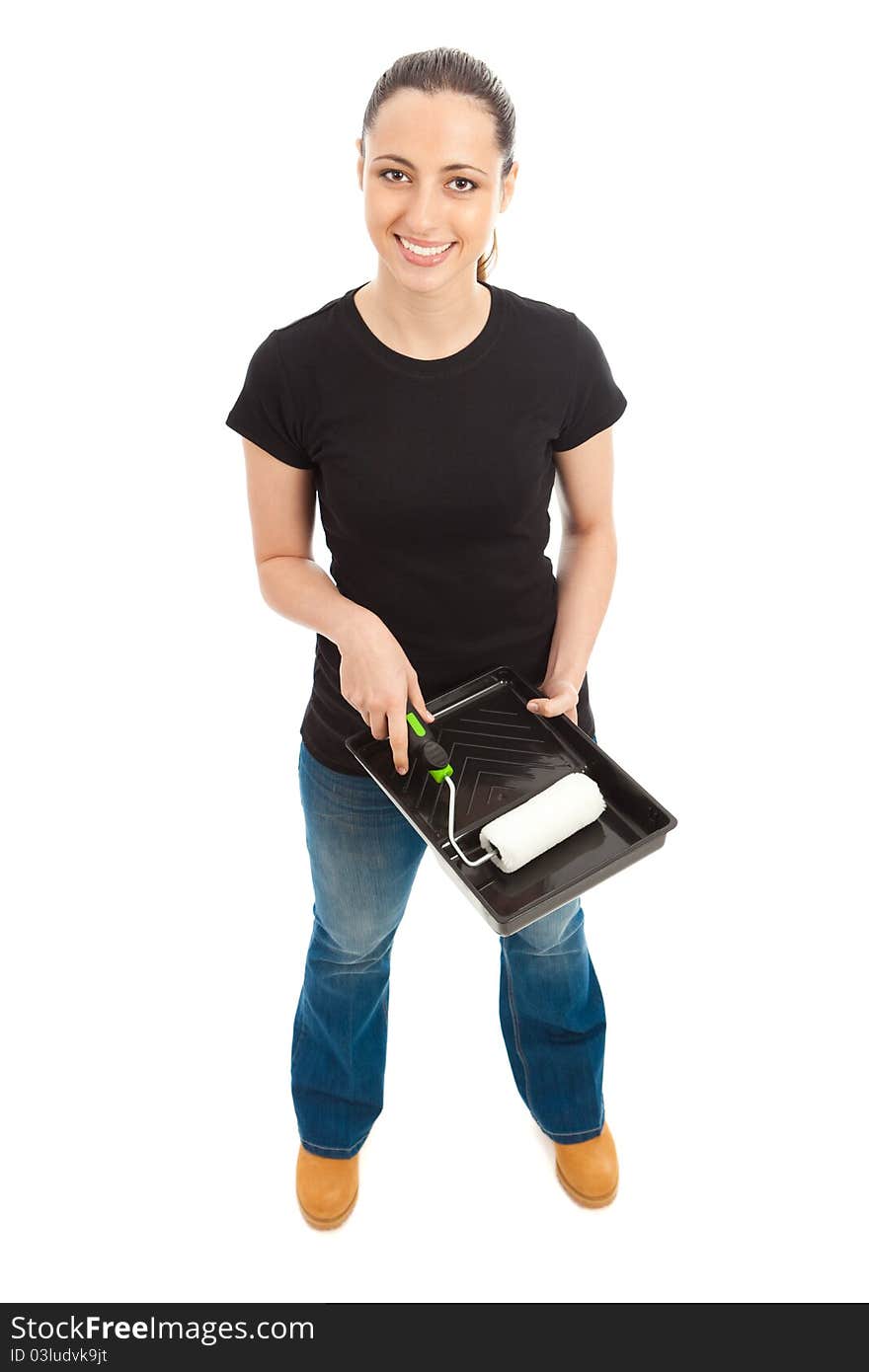 A young female dressed in a black t shirt and blue jeans holding a paint roller and tray. A young female dressed in a black t shirt and blue jeans holding a paint roller and tray