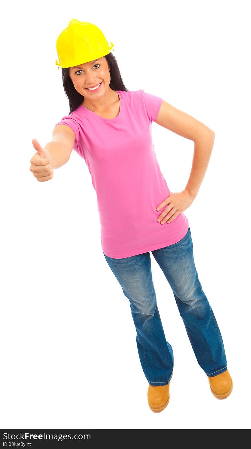 A young female dressed in blue jeans and pink top and yellow hard hat giving the thumbs up sign. A young female dressed in blue jeans and pink top and yellow hard hat giving the thumbs up sign