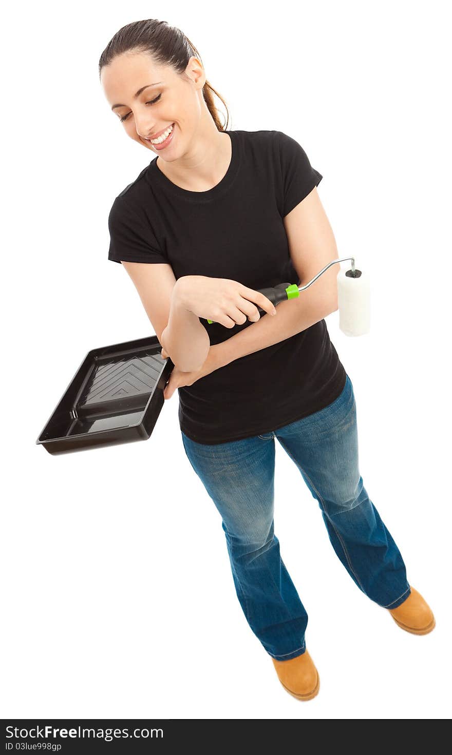 A young female dressed in a black t shirt and blue jeans holding a paint roller and tray. A young female dressed in a black t shirt and blue jeans holding a paint roller and tray