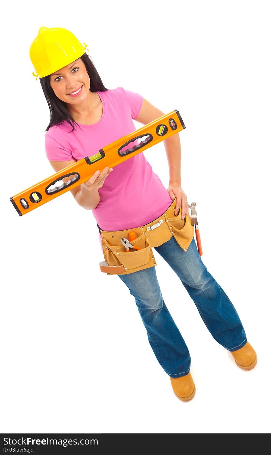 A young female dressed in blue jeans and pink top  and yellow hard hat holding a spirit level. A young female dressed in blue jeans and pink top  and yellow hard hat holding a spirit level