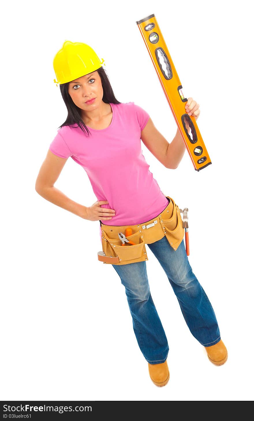 A young female dressed in blue jeans and pink top and yellow hard hat holding a spirit level. A young female dressed in blue jeans and pink top and yellow hard hat holding a spirit level