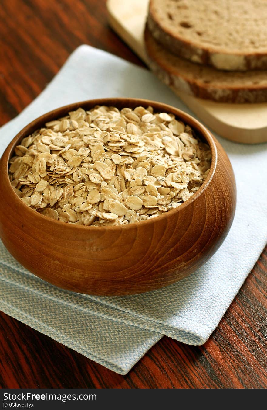 Oats in wooden bowl and bread on table