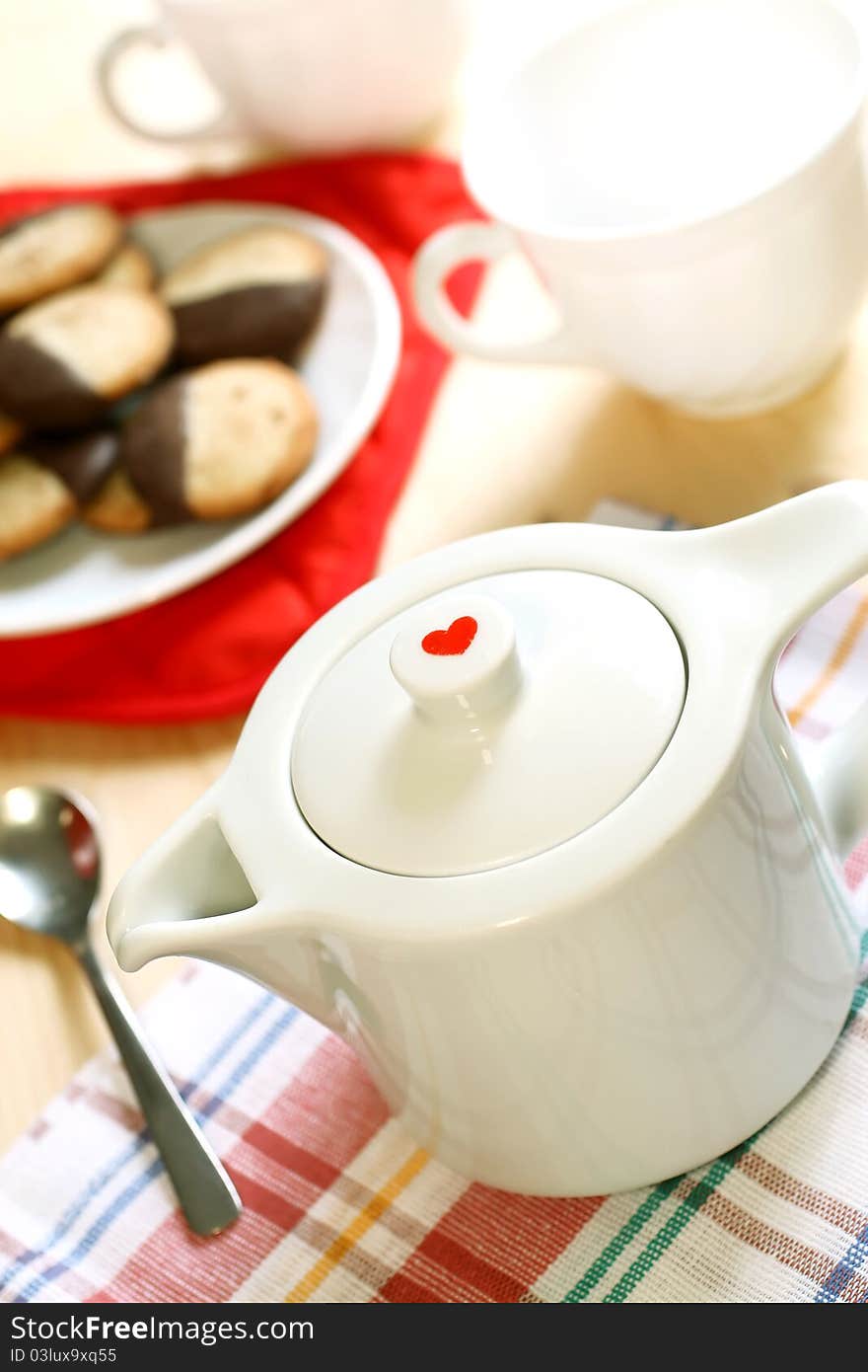 Teapot with red heart, cup and cookies