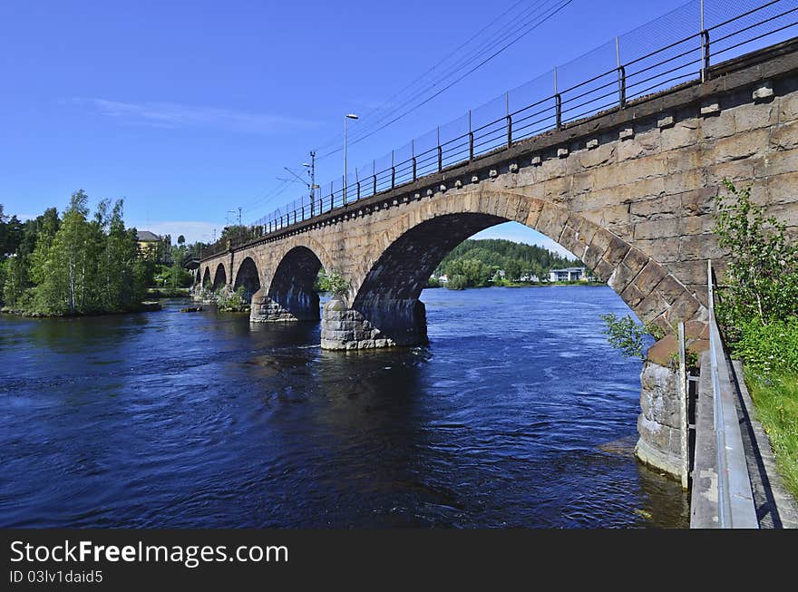 The old railway bridge crosses the beautifully blue Begna River just a hundred yards above the Hoenefoss Falls.