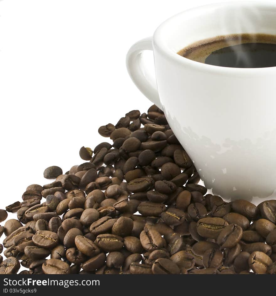 Coffee in a white cup stands on grains of coffee on a white background. Coffee in a white cup stands on grains of coffee on a white background