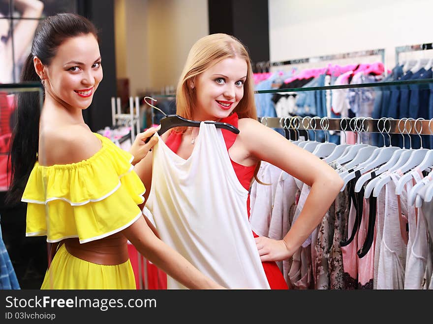 Two young beautiful girls choose their clothes in the store