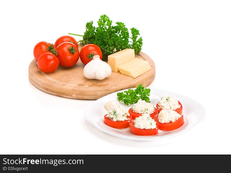 Sliced tomato with cheese and garlic sauce on a plate. Ingedients on a board. Sliced tomato with cheese and garlic sauce on a plate. Ingedients on a board.