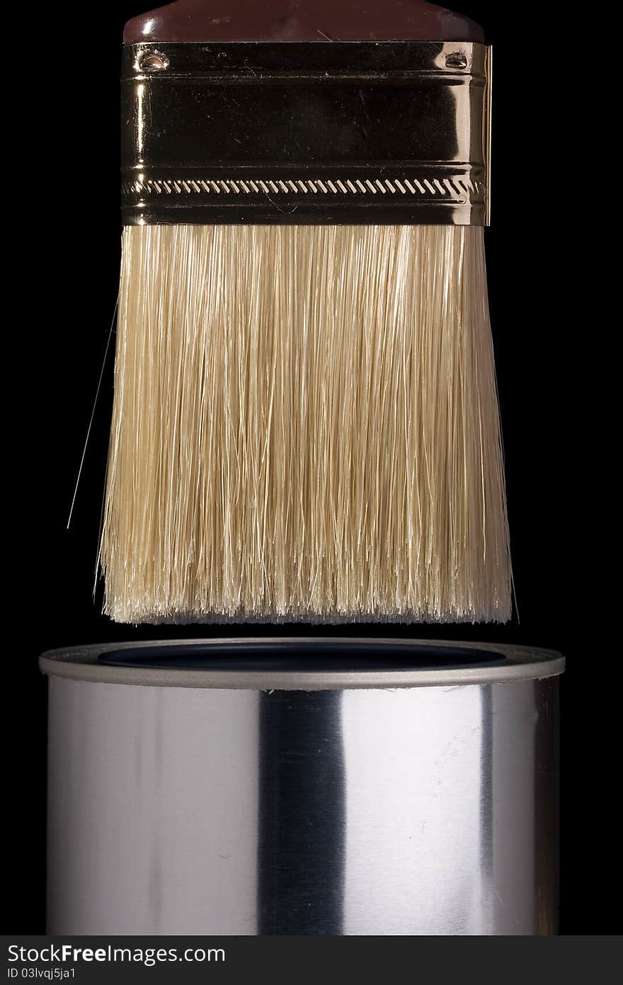 Clean paintbrush dipping into a silver can. Clean paintbrush dipping into a silver can.