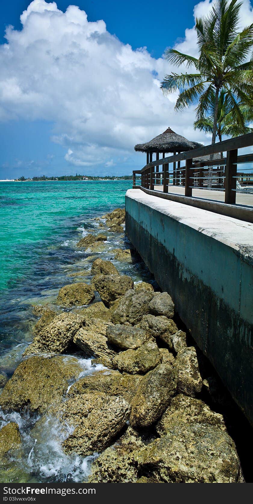 Beach hut overlooking rocks, a bulkhead, and caribbean island lagoon. Beach hut overlooking rocks, a bulkhead, and caribbean island lagoon