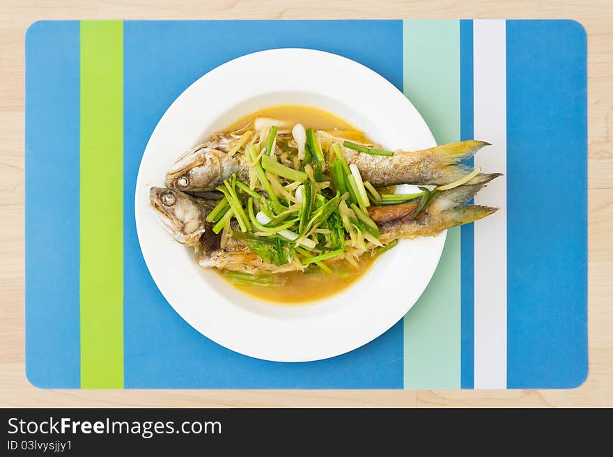 Two steamed mackerel fishes with ginger on white plate