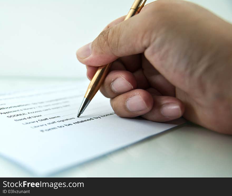 A hand, holding a pen, is ready to sign a document. A hand, holding a pen, is ready to sign a document.