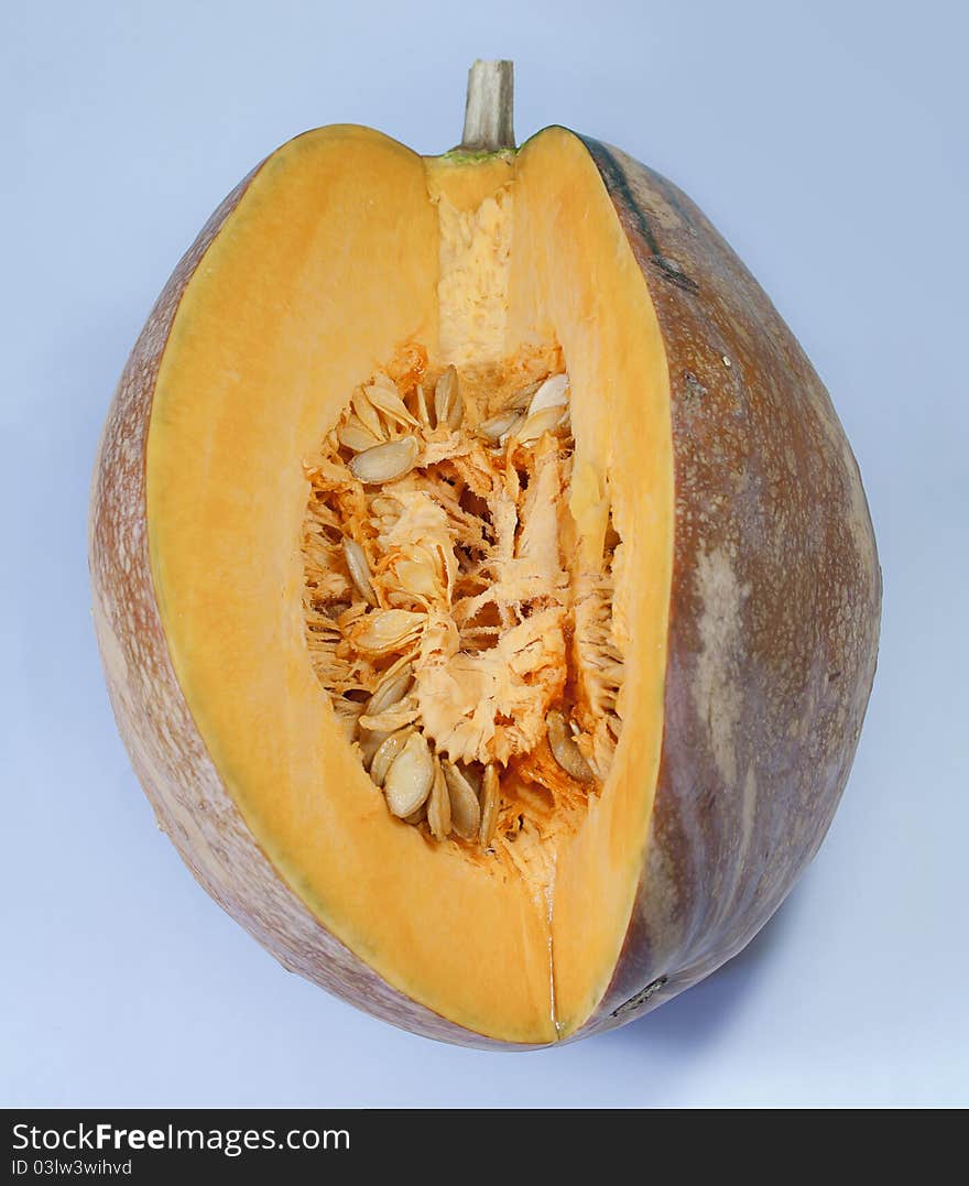 This is a mature pumpkin, was on a blue background, cutting a piece of, revealing the many seeds