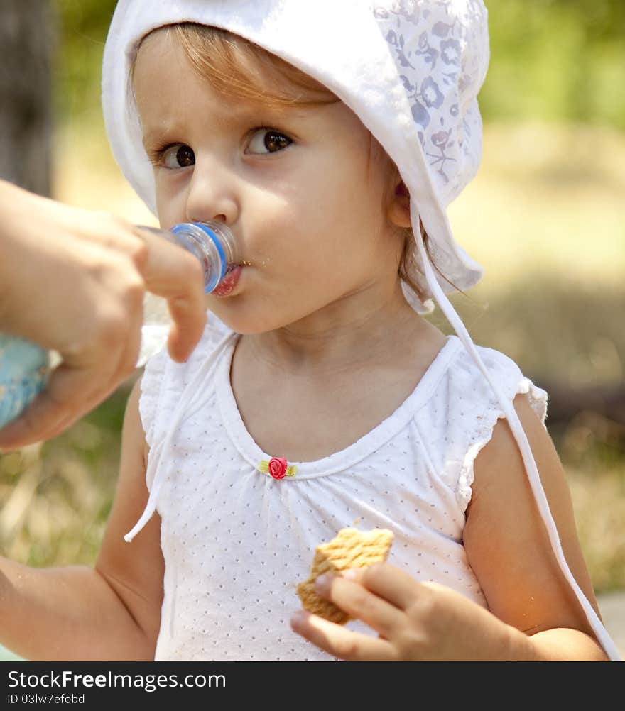 Little girl dring water in the park.