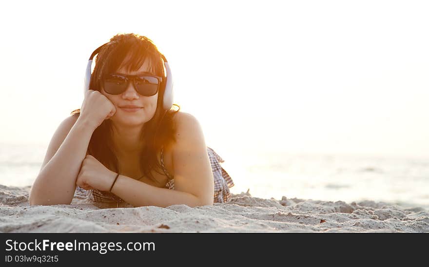 Beautiful brunette girl with headphones at beach sand.