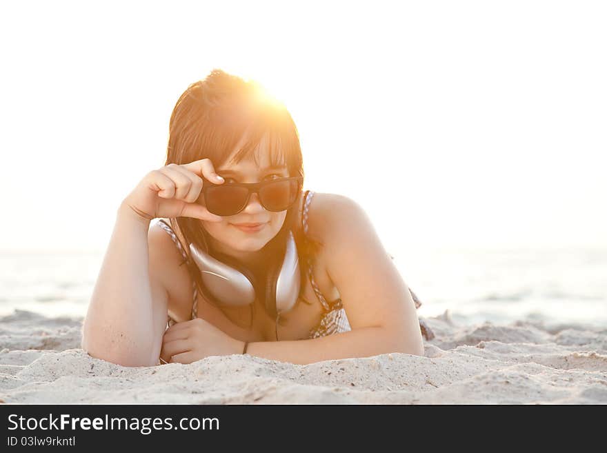 Beautiful brunette girl with headphones at beach sand.