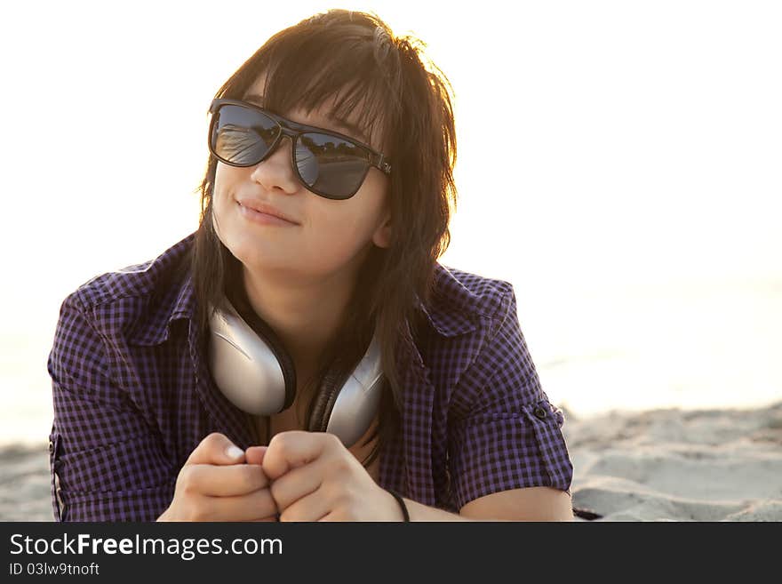 Beautiful brunette girl with headphones at beach sand.