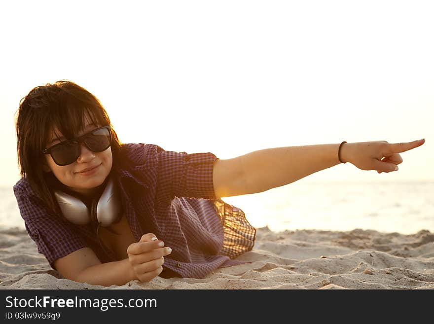 Beautiful brunette girl with headphones at beach sand.