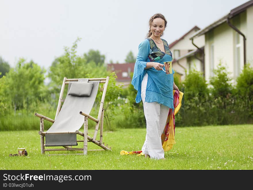 Cute woman with cup near a deck chair. Cute woman with cup near a deck chair